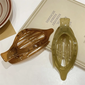 Dettaglio di fermagli per capelli ovali color ambra e verde con design a traforo su libro