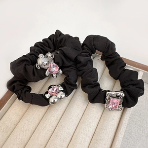 Three black satin scrunchies with silver bear and pink crystal charms on velvet tray