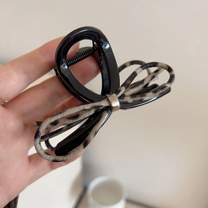 Brown leopard print bow claw clip with silver buckle shown in hand for scale
