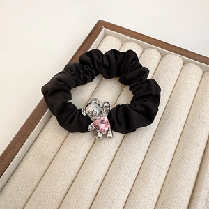 Close-up of black hair scrunchie with silver metal bear charm and pink heart crystal