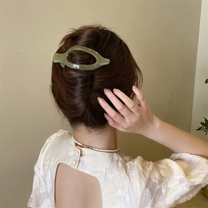 Dettaglio della clip per capelli traslucida verde chiaro per fissare uno chignon francese