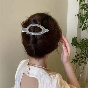 Dettaglio di un fermaglio per capelli opaco traslucido in un'acconciatura elegante