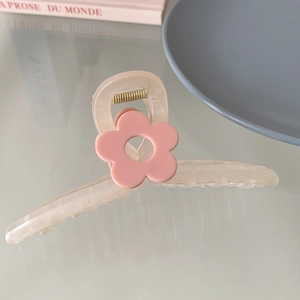 Détail de la pince à cheveux crème avec une fleur rose sur fond de bureau doux