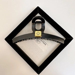 Detailed view of matte black large hair claw clip featuring a golden smiley face accent