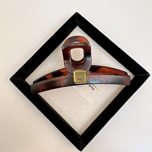 Elegant tortoise shell claw clip with a golden square smiley face charm for hair styling