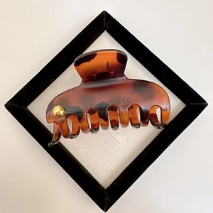 Elegant tortoise shell hair claw with gold accent in a velvet display frame