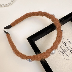 Detail of brown knitted headband featuring white pearls and a sparkling zircon gem