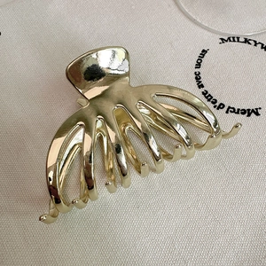 Polished gold metal hair claw clip with minimalist curved hollow design for women