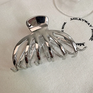 Minimalist silver metal shark hair claw clip shown in a 45-degree angle top view