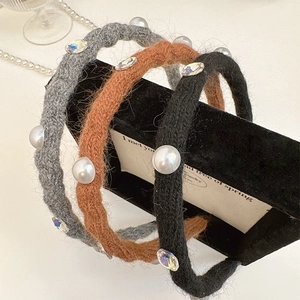 Close-up of three knitted headbands with pearls and crystals on a velvet display stand