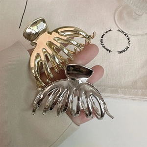 Close-up of gold and silver metallic large hair claws with a polished glossy finish