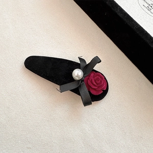 Elegant red velvet rose hair clip with black silk bow and pearl on ivory fabric