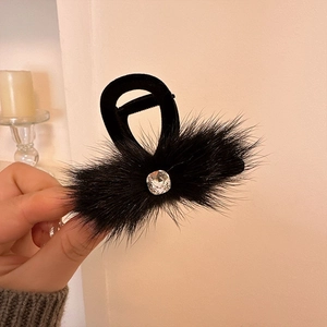 Detail of a black plush hair claw clip featuring a square sparkling rhinestone accent