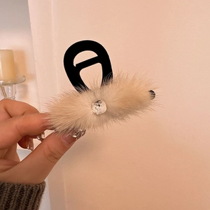 Macro detail of the plush faux fur texture and square rhinestone on the claw hair clip
