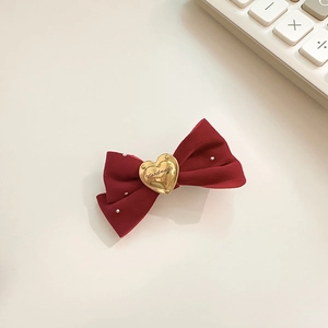 Détail d'un nœud papillon en velours bordeaux avec cœur doré et petites perles