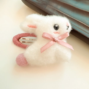 Close-up of a handmade white plush bunny hair clip with a pink bow and fabric-covered clip