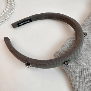 Detail of grey knitted padded headband with crystal beads and handmade woven label