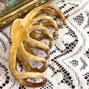 Close-up of amber marble hair claw clip with multi-tooth structure on lace tablecloth