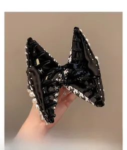 Detailed close-up of large houndstooth hair claw clip with elegant pearl embellishments