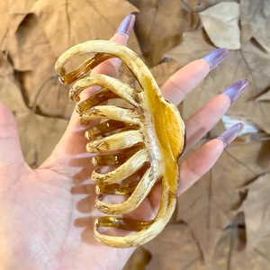 Detail view of large amber marble hair claw clip with glossy finish and toothed design