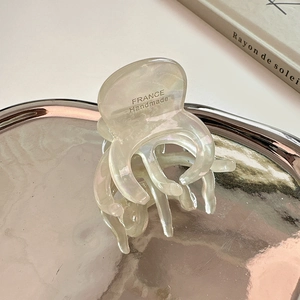 Détail de la pince à cheveux artisanale en acétate nacré avec gravure sur plateau miroir