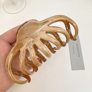 Detail of large brown marble resin hair claw clip with smooth teeth for daily styling