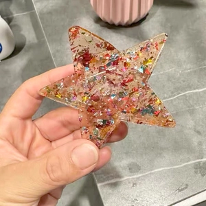 Close-up of star-shaped hair claw with multi-colored foil sequins in resin material