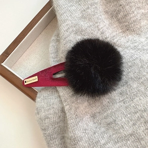 Détail de la pince à cheveux pompon noir avec velours bordeaux et étiquette dorée