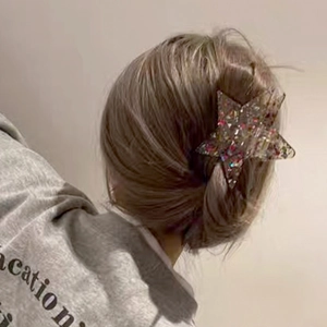 Star shaped hair claw clip with multicolored glitter and sequins worn on a model hair