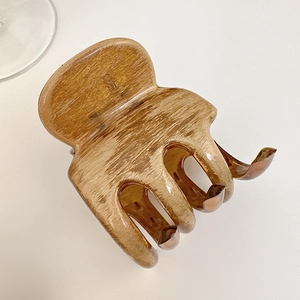 Detailed top view of large amber wood grain hair claw clip with glossy finish
