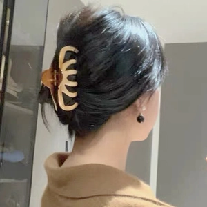 Detail view of a large amber hair claw clip securing a bun hairstyle from the back