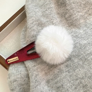 Détail d'une barrette BB en velours bordeaux avec pompon blanc et étiquette dorée Handmade