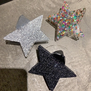 Detailed view of star-shaped hair claws in silver, black glitter and colorful sequins