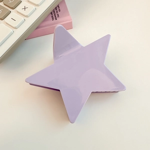 Close-up of lavender star-shaped hair claw clip on desk with accessories