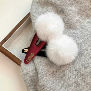 Détail de pinces à cheveux en peluche blanche avec étiquette dorée sur base en velours