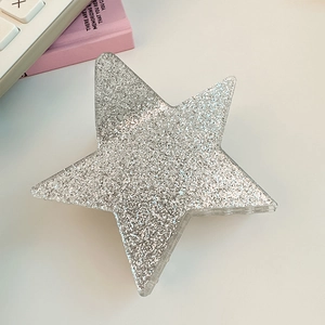 Close-up of a silver star-shaped hair claw clip with shimmering glitter finish on white desk