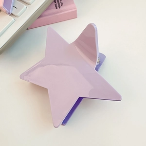 Detailed close-up of a light purple star hair claw clip on a clean white desk setup
