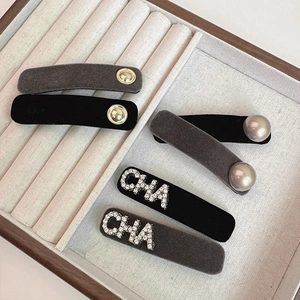 Detail of elegant flocked hair clips with pearls, gold buttons and rhinestone CHA lettering