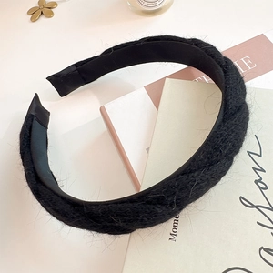 Detail eines schwarzen gestrickten Knotenstirnbands mit weicher Wollstruktur und Futter