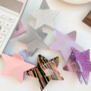 Star shaped hair claw clips in silver glitter, purple, and striped patterns on white background