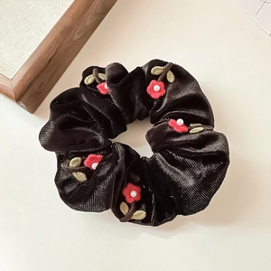 Detail of black velvet scrunchie with red flower embroidery and pearl accents