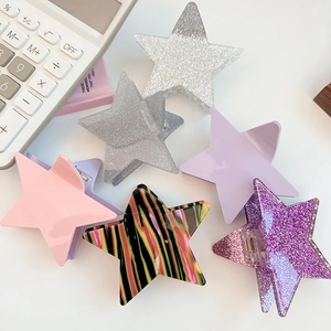 Detailed view of six star-shaped hair clips in glitter and glossy finishes on a desk