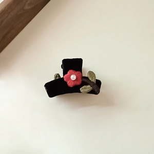 Detail of black velvet hair clip featuring red embroidered flower with white pearl and green leaves