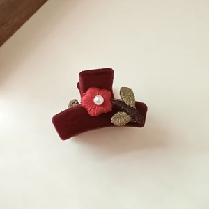 Detail view of burgundy velvet hair claw with embroidered flowers and pearl accent