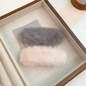 Elegant plush faux fur hair clips in beige and grey on a wooden tray for women