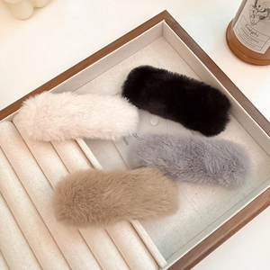 Detailed set of four plush hair clips in black, white, grey, and brown in a wooden tray