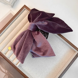 Pince à cheveux noeud en velours violet foncé avec pendentif doré sur plateau