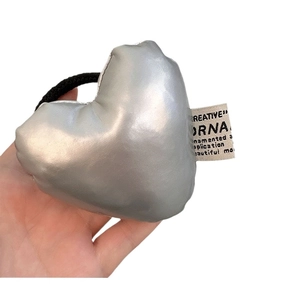 3D Metallic Silber Herz Haargummi mit stylischem gewebtem Etikett auf weißem Grund
