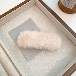 Detailed texture of minimalist cream plush hair clip on a decorative wooden tray