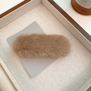Macro shot of fluffy camel plush oval hair clip on textured display card for winter